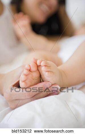 Close up of mixed race mother holding feet of baby View Large Photo Image Stock Image - Close up of mixed race mother holding feet of baby. Fotosearch