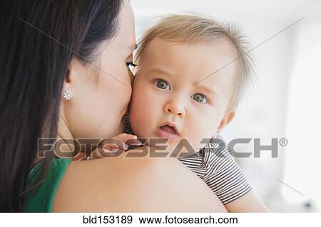 Stock Photo - Close up of mixed race mother holding baby. Fotosearch