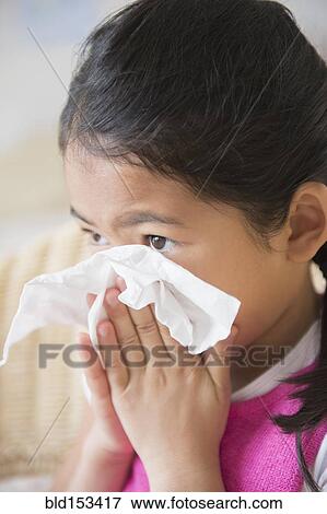 Stock Photo - Close up of Vietnamese girl blowing her nose. Fotosearch