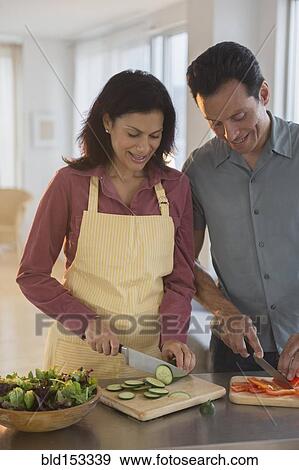 Stock Photo - Couple chopping vegetables in kitchen. Fotosearch