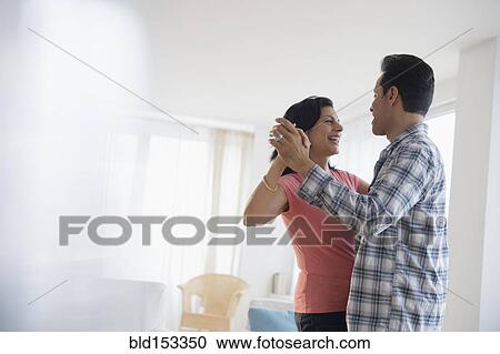 Stock Image - Couple dancing in living room. Fotosearch
