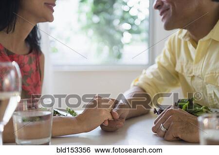 Stock Photograph - Couple holding hands in restaurant. Fotosearch