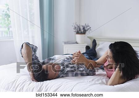 Couple holding hands on bed View Large Photo Image Picture - Couple holding hands on bed. Fotosearch
