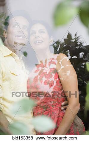 Stock Photo - Couple hugging and looking out window. Fotosearch