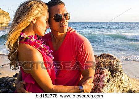 Stock Photo - Couple hugging near rock formation on beach. Fotosearch