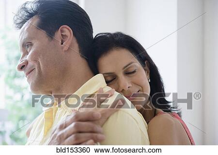 Stock Image - Couple hugging near window. Fotosearch