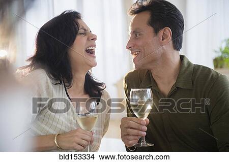 Picture - Couple laughing and drinking white wine. Fotosearch