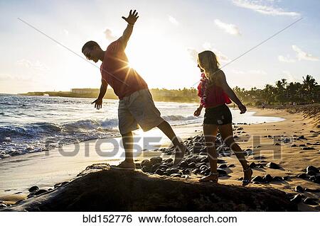 Stock Photograph - Couple playing on rocks on beach. Fotosearch