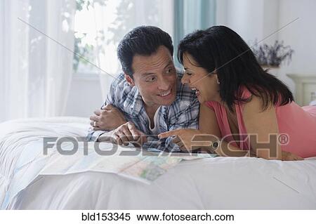 Stock Photography - Couple reading map on bed. Fotosearch