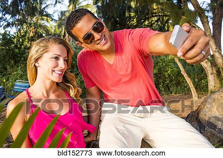 Couple taking cell phone photograph outdoors View Large Photo Image Stock Image - Couple taking cell phone photograph outdoors. Fotosearch