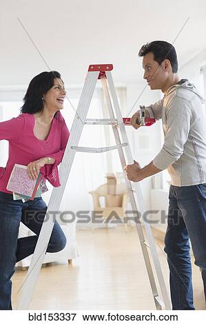 Stock Photo - Couple talking at ladder during home remodeling. Fotosearch
