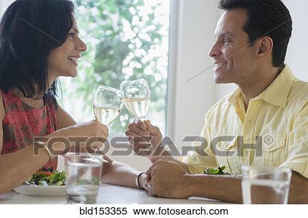 Couple toasting each other with white wine in restaurant View Large Photo Image Stock Photography - Couple toasting each other with white wine in restaurant. Fotosearch