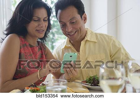 Couple using cell phone in restaurant View Large Photo Image Picture - Couple using cell phone in restaurant. Fotosearch