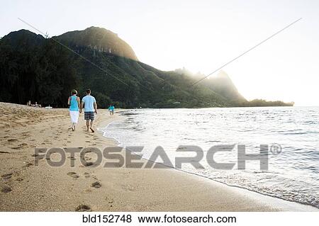 Stock Photo - Couple walking together near ocean on beach. Fotosearch