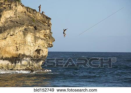 Divers jumping off cliff into ocean View Large Photo Image Stock Photo - Divers jumping off cliff into ocean. Fotosearch