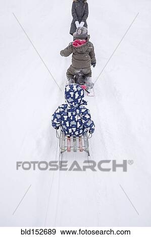 Stock Photo - Family playing on sleds on snowy street. Fotosearch