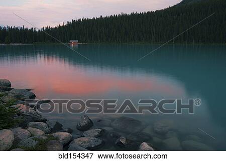 Forest treetops reflecting in still remote lake View Large Photo Image Stock Photo - Forest treetops reflecting in still remote lake. Fotosearch