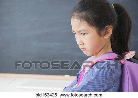 Stock Photography - Frowning Vietnamese girl standing in classroom. Fotosearch
