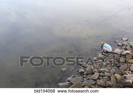 Stock Photo - High angle view of Caucasian girl playing at lake. Fotosearch
