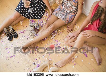 Stock Photography - High angle view of women sitting on floor with confetti after party. Fotosearch