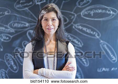 Stock Image - Hispanic businesswoman smiling by flow chart on blackboard. Fotosearch