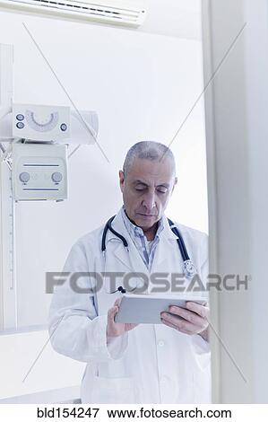 Stock Photo - Hispanic doctor using digital tablet in hospital. Fotosearch