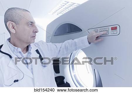 Stock Image - Hispanic doctor using MRI scanner. Fotosearch