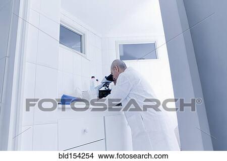 Picture - Hispanic scientist using microscope in lab. Fotosearch