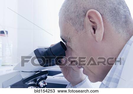 Stock Image - Hispanic scientist using microscope in lab. Fotosearch