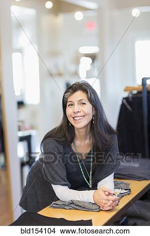Picture - Hispanic small business owner smiling in store. Fotosearch