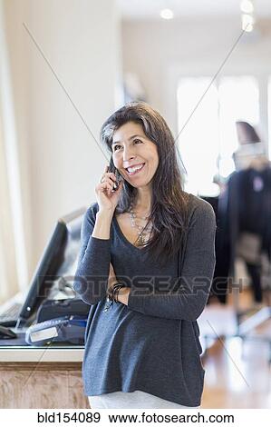 Hispanic small business owner talking on telephone View Large Photo Image Stock Photo - Hispanic small business owner talking on telephone. Fotosearch