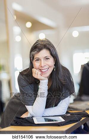 Stock Photograph - Hispanic small business owner using digital tablet in store. Fotosearch