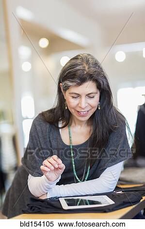 Stock Photography - Hispanic small business owner using digital tablet in store. Fotosearch
