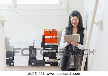 Stock Image - Hispanic woman using digital tablet in office. Fotosearch