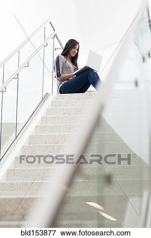 Hispanic woman using laptop on staircase View Large Photo Image Stock Photo - Hispanic woman using laptop on staircase. Fotosearch