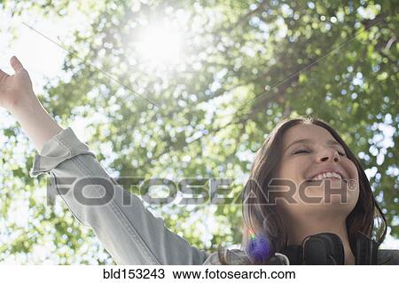 Stock Image - Low angle view of Caucasian woman cheering outdoors. Fotosearch