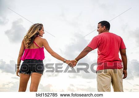 Low angle view of couple holding hands under cloudy sky View Large Photo Image Stock Photography - Low angle view of couple holding hands under cloudy sky. Fotosearch