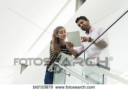 Low angle view of couple using digital tablet View Large Photo Image Stock Photo - Low angle view of couple using digital tablet. Fotosearch