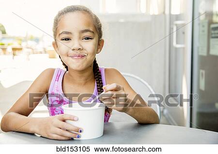 Mixed race girl eating ice cream at outdoor cafe View Large Photo Image Stock Photography - Mixed race girl eating ice cream at outdoor cafe. Fotosearch