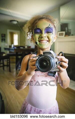 Stock Photograph - Mixed race girl in face paint photographing with camera. Fotosearch