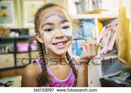 Mixed race girl painting her face in bedroom View Large Photo Image Stock Photo - Mixed race girl painting her face in bedroom. Fotosearch
