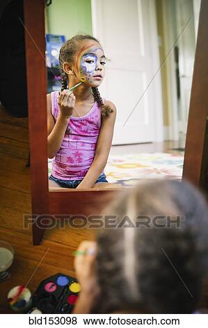 Mixed race girl painting her face in bedroom View Large Photo Image Stock Photo - Mixed race girl painting her face in bedroom. Fotosearch