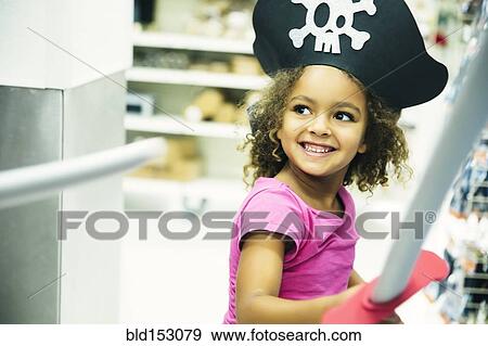 Stock Photo - Mixed race girl playing dress-up with pirate hat and sword. Fotosearch