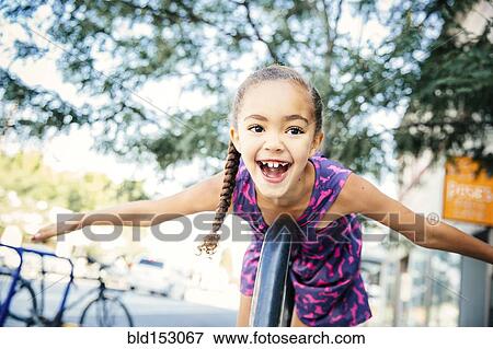 Stock Photo - Mixed race girl playing on bicycle rack. Fotosearch