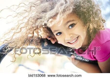 Stock Photo - Mixed race girl playing on bicycle rack. Fotosearch
