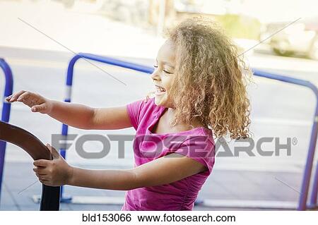 Stock Photograph - Mixed race girl playing on bicycle rack. Fotosearch