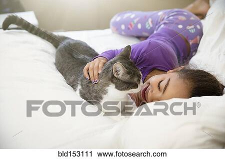 Mixed race girl playing with cat on bed View Large Photo Image Stock Image - Mixed race girl playing with cat on bed. Fotosearch