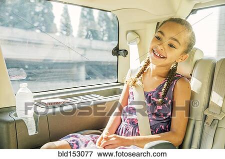 Stock Photo - Mixed race girl smiling in back seat of car. Fotosearch