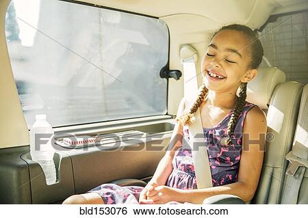 Stock Photograph - Mixed race girl smiling in back seat of car. Fotosearch