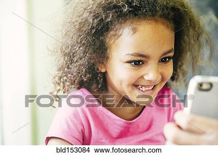 Mixed race girl using cell phone at home View Large Photo Image Picture - Mixed race girl using cell phone at home. Fotosearch
